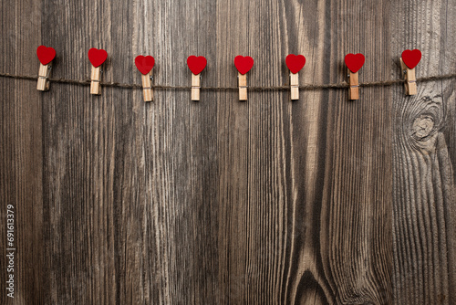 eight decorative clothespins with hearts suspended on a rope on a wooden background for stickers, photos and letters; love; valentine's day card;