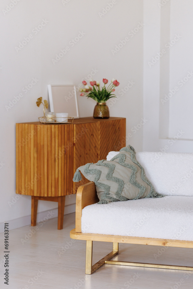 Naklejka premium Modern living room featuring a white couch, wooden sideboard, and a vase of flowers. A white curtain with small lights forms the backdrop. Concept: Cozy home interior. Copy space available.