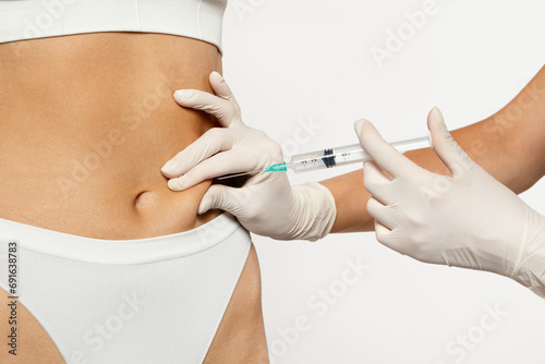 A gloved medical professional is carefully administering subcutaneous injection in abdomen