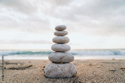 A cairn of smooth stones stacked on the sand symbolizes balance and tranquility by the sea