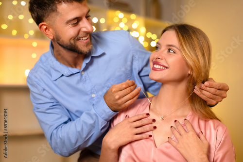 Man affectionately gifting a necklace to a delighted woman photo