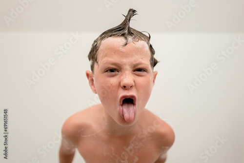 Funny little boy showing tongue out in bathroom photo