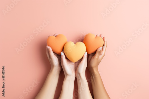  Hands holding peach color hearts. St. Valentine's day background. Peach color background. Space for text. photo