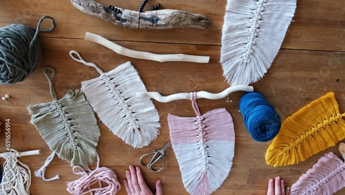 Top down view of woman making boho macrame feathers. Knitting macrame wall decor DIY. Flat lay of woman hands with macrame leaf or feather photo