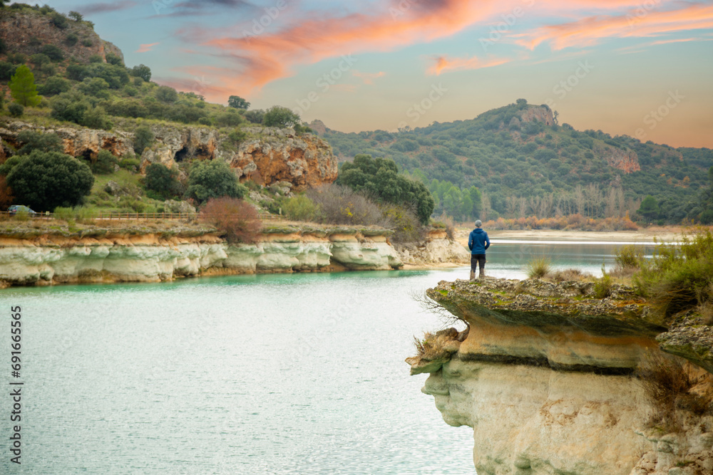 Person alone contemplating the lake from a cliff and enjoying nature in the lagoons of Ruidera Person alone contemplating the lake from a cliff and enjoying nature in the lagoons of Ruidera