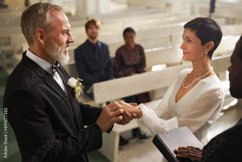 Φωτογραφία Side view portrait of smiling senior couple exchanging rings during wedding cere