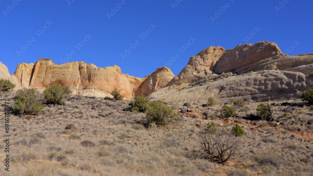 Establishing shot of mountain trail with red rocks background in Hickman Natural Bridge Trail, Capital Reef National Park, Utah, North America. Day time on October 2023. Still camera view. ProRes 422 Establishing shot of mountain trail with red rocks background in Hickman Natural Bridge Trail, Capital Reef National Park, Utah, North America. Day time on October 2023. Still camera view. ProRes 422