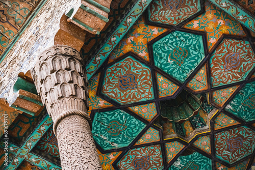 Wooden column support on the facade of a building supports the roof in the ancient city of Khiva in Khorezm, wood carvings and traditional patterns on the ceiling, interior photo