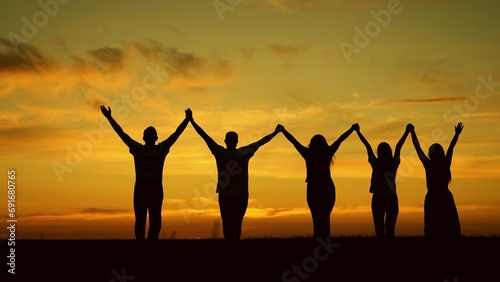 Team of people look at their future together at sunset, park. Group of business people outdoors raise their hands to sky. Human resources. Community of people joint prayer. Unity of group of people
