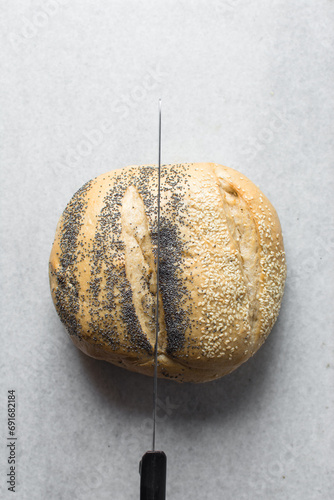 Top view of round homemade bread on a linen napkin, Potbrood coated with sesame seeds	 photo