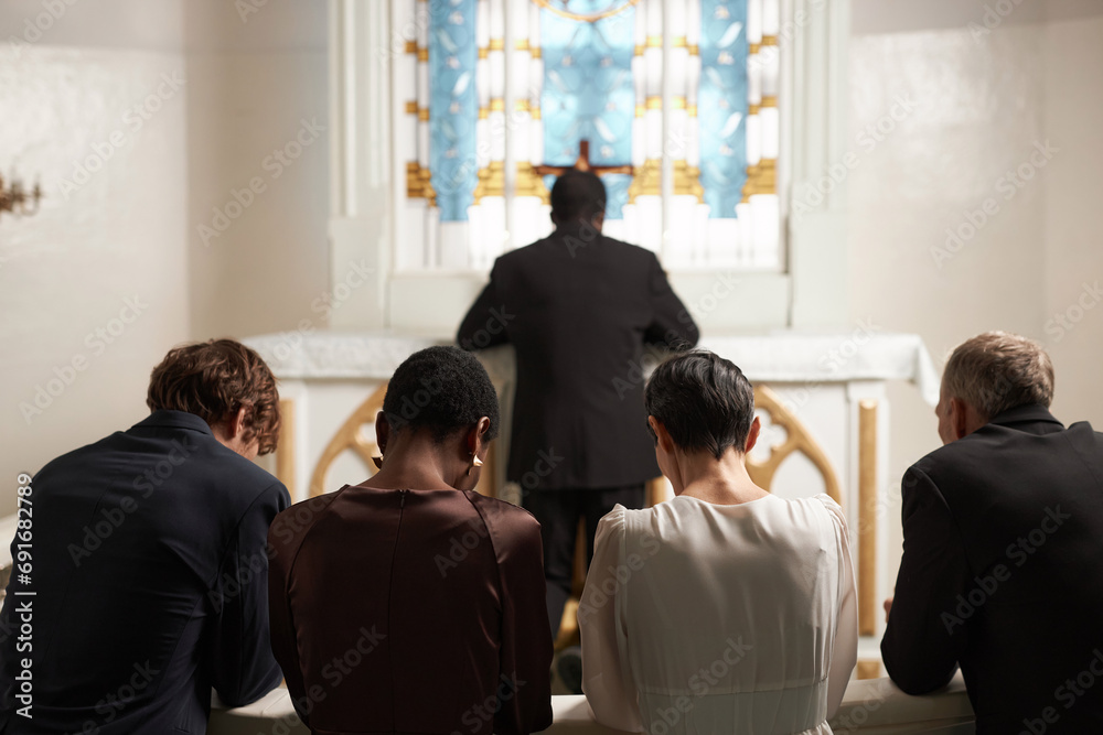 Back view of group of young people praying silently together during Sunday service in Catholic church - obrazy, fototapety, plakaty 