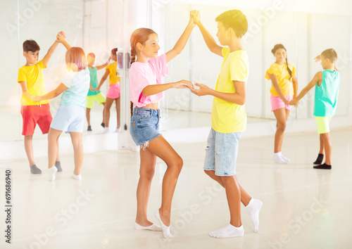 Happy boys and girls enjoying active dance in studio