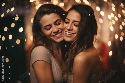 Caucasian young women hugging each other outside under falling snow during festive party. Friends or lesbian couple happy together. Girls sisters walking outdoor in winter. LGBT love friendship