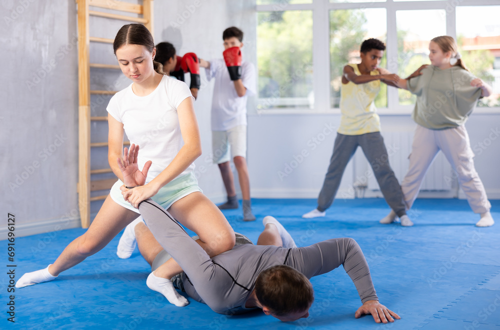 Fototapeta premium Coach man and girl training self-defense techniques in studio..