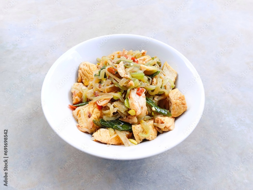 stir-fry chayote mixed with tofu and bean sprouts. Indonesia traditional food. Sayur welok atau labu siam dan tahu. spicy chayote cooked with tofu and bean sprouts in bowl on gray background. homemade
