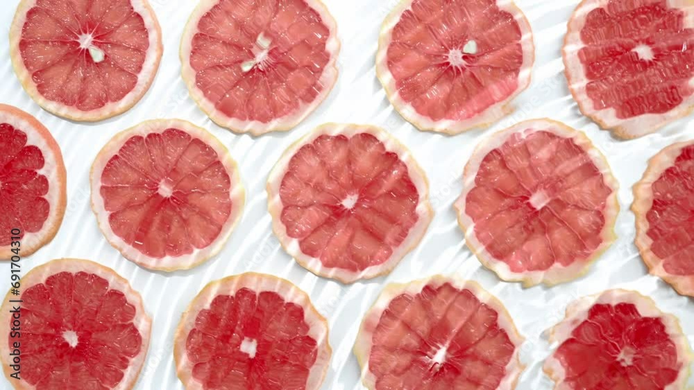 Slice of grapefruit underwater or in water with splashing and droplet top view flat lay on white background. Slice of grapefruit underwater or in water with splashing and droplet top view flat lay on white background.
