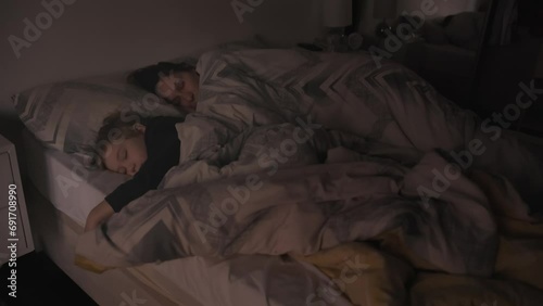 A mom and three years old little son is sleeping in the bed photo