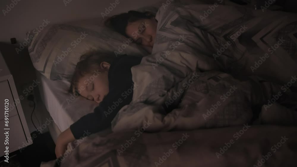 A mammy and three years old little son is sleeping in the bed A mammy and three years old little son is sleeping in the bed