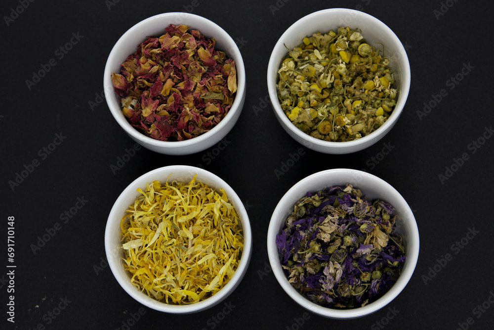 Dried flower petals in white bowls, on black background Dried flower petals in white bowls, on black background