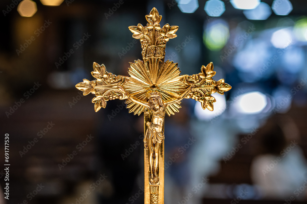 Crucifixo católico dourado com jesus e fundo desfocado