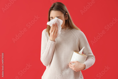 Ill young woman with tissues on red background