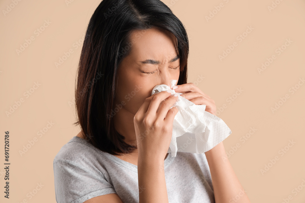 Ill Asian woman with tissues on beige background, closeup Ill Asian woman with tissues on beige background, closeup