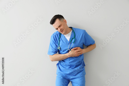 Male doctor having heart attack on light background