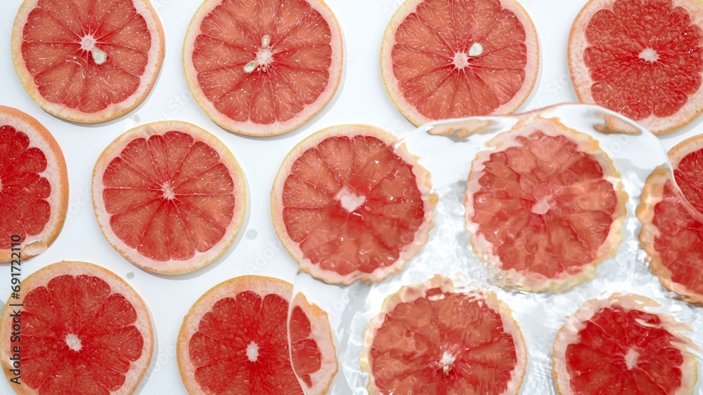 Slice of grapefruit underwater or in water with splashing and droplet top view flat lay on white background. Slice of grapefruit underwater or in water with splashing and droplet top view flat lay on white background.