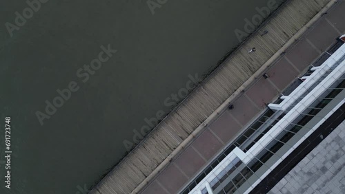 people walking on a dock on the jersey city waterfront (aerial drone shot looking down) pedestrian bike path boardwalk (urban, industrial, river water) still, flying up turning down establishing shot photo