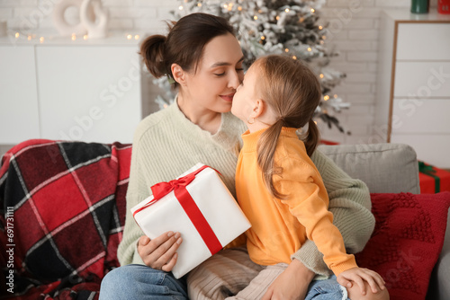Young mother with her little daughter touching noses at home on Christmas eve