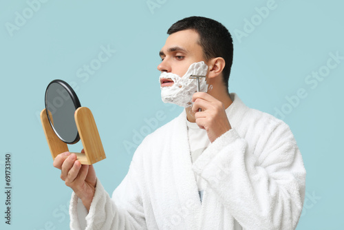 Young man shaving face with...