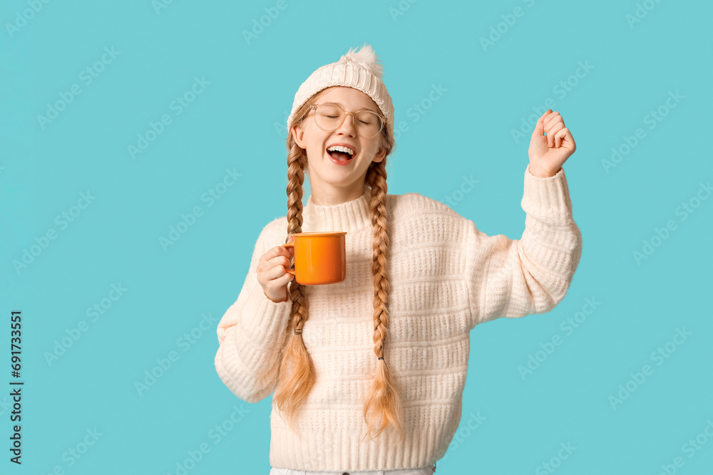 Beautiful young happy woman in warm winter clothes with cup of tea on blue background Beautiful young happy woman in warm winter clothes with cup of tea on blue background