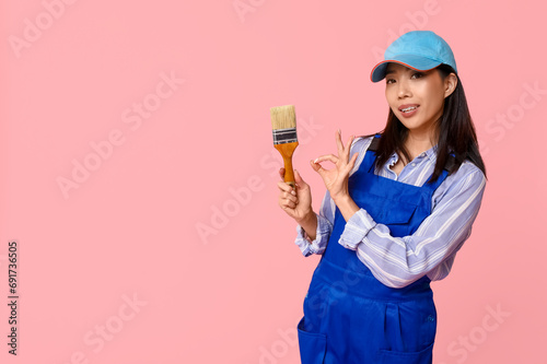 Female Asian painter with brush on pink background
