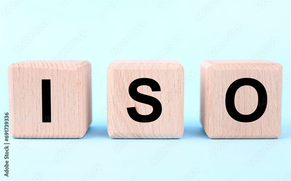International Organization for Standardization. Wooden cubes with abbreviation ISO on light blue background, closeup International Organization for Standardization. Wooden cubes with abbreviation ISO on light blue background, closeup