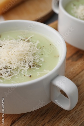 Delicious cream soup with parmesan cheese in bowls on wooden board, closeup