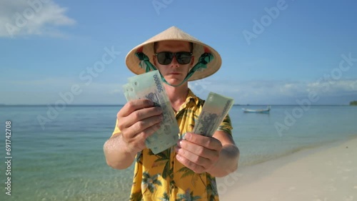 Man counting Vietnamese Dong on the tropical beach in Vietnam. photo