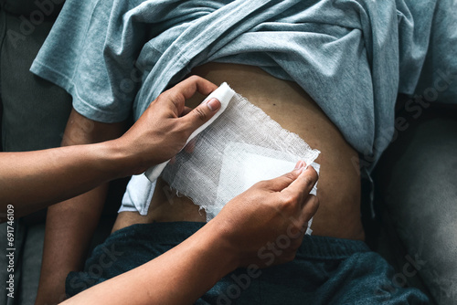 Doctor's hand applying bandage to patient stomach in the clinic, post appendectomy surgery photo