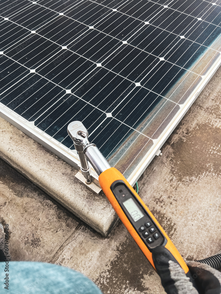 close up of a worker with a torque meter in a solar panel installation