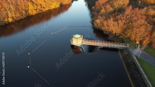 Fresh water reservoir with plug hole. English lake with Autumnal trees at golden hour photo