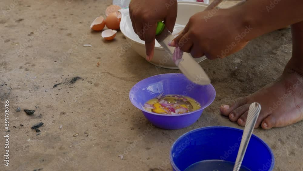Preparation of omelet to accompany with banku dumpling, african woman chops onion and adds it to beaten egg on a plate, Ghana Preparation of omelet to accompany with banku dumpling, african woman chops onion and adds it to beaten egg on a plate, Ghana