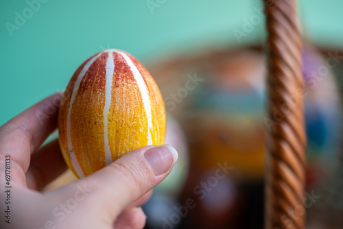 mano de mujer sosteniendo huevo cocido decorado como huevo de pascua