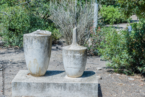Ancient stone urns on concrete plinths in garden part of the Agora ruins in Athens, Greece.