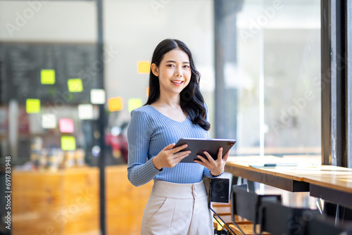 Happy asian businesswoman planning new project with sticky note in a creative writing on blank office glass