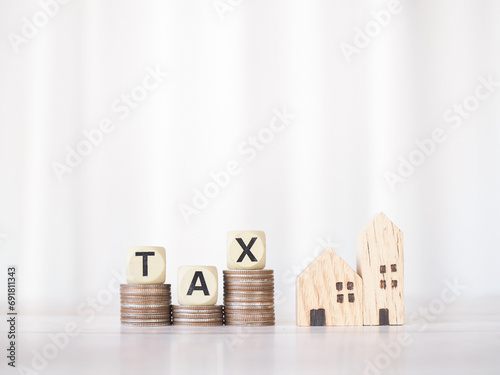 Miniature house, Wooden blocks with the word TAX on stack of coins. The concept of payment tax for house, Property investment, House mortgage, Real estate. photo