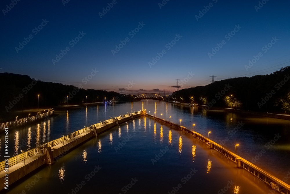 This nighttime image captures the lock guidance lights along a canal, providing a safe passage for nocturnal marine navigation. The lights create a luminous trail on the water, reflecting the