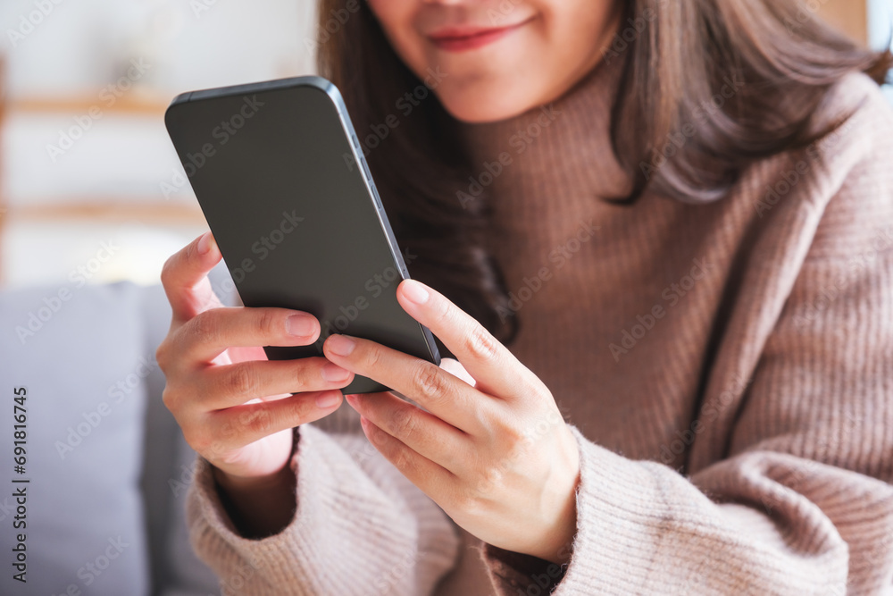 Closeup image of a young woman holding and using smart phone at home Closeup image of a young woman holding and using smart phone at home