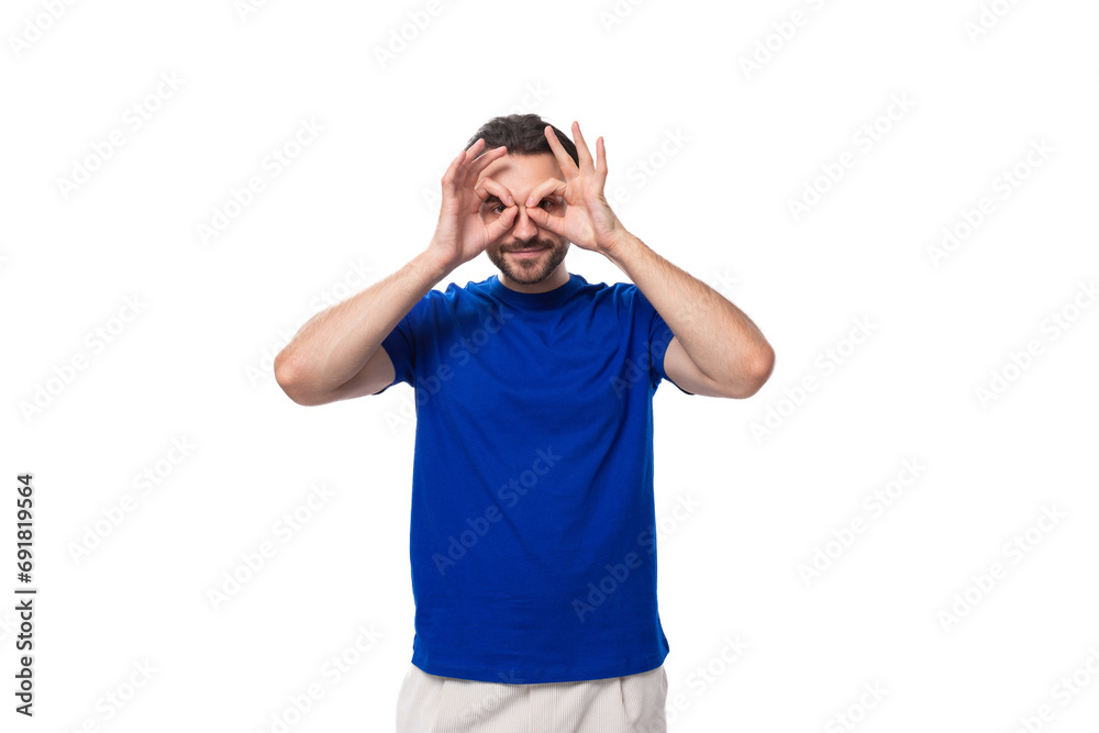 Fototapeta premium young attractive brunette man with a beard in a blue t-shirt with a mockup on a white background with copy space