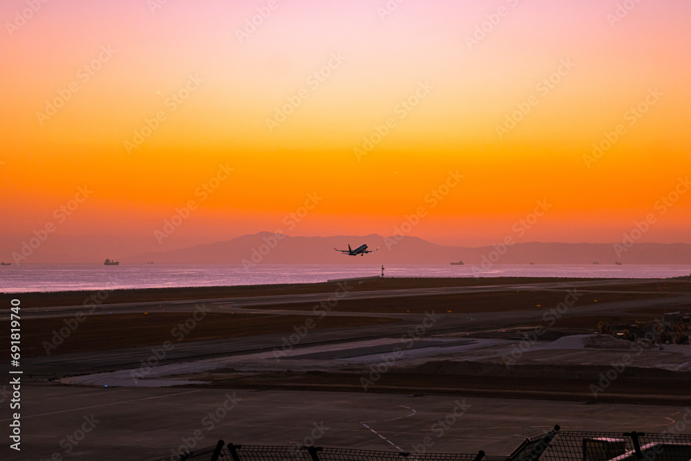 Obraz premium 夕暮れ時の空を飛ぶ飛行機