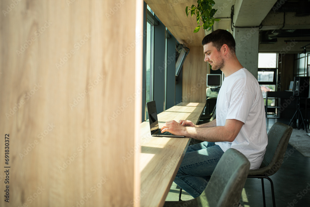 A cheerful young entrepreneur works in a modern workspace A cheerful young entrepreneur works in a modern workspace