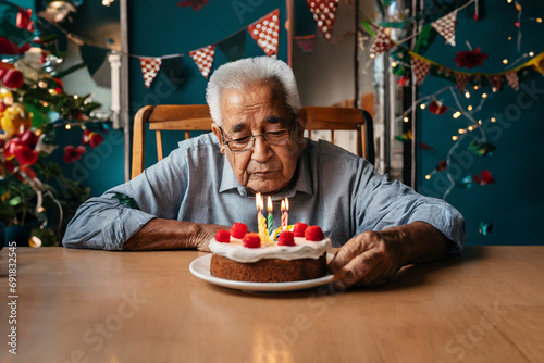 sad or depressed or angry grandpa, old man on birthday, on a chair at a table with a birthday cake photo